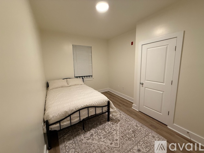 A bedroom with a bed, a rug, and a door.