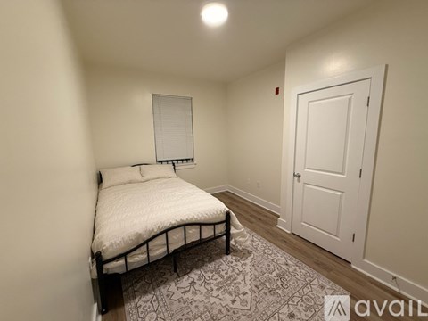 A bedroom with a bed, a rug, and a door.