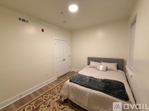 A bedroom with a bed, pillows, and a rug.