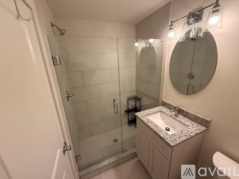 A bathroom with a sink, mirror, and shower.