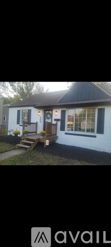 A white house with a black roof and a wooden bench in front.