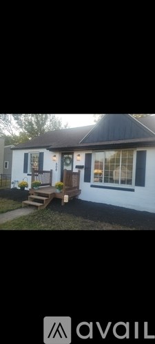 A white house with a black roof and a wooden bench in front.