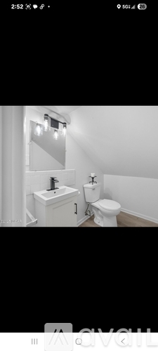 A white bathroom with a toilet, sink, and mirror.