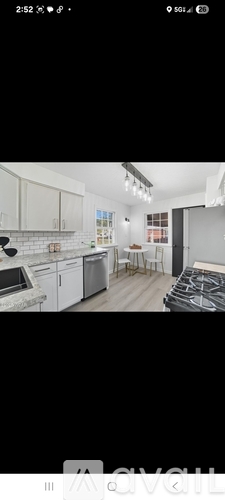 A modern kitchen with white cabinets and a black stove top.