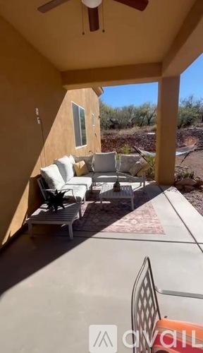 A patio with white furniture and a ceiling fan.