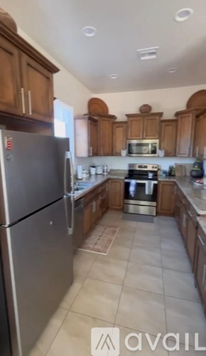 A kitchen with wooden cabinets and a stainless steel refrigerator.