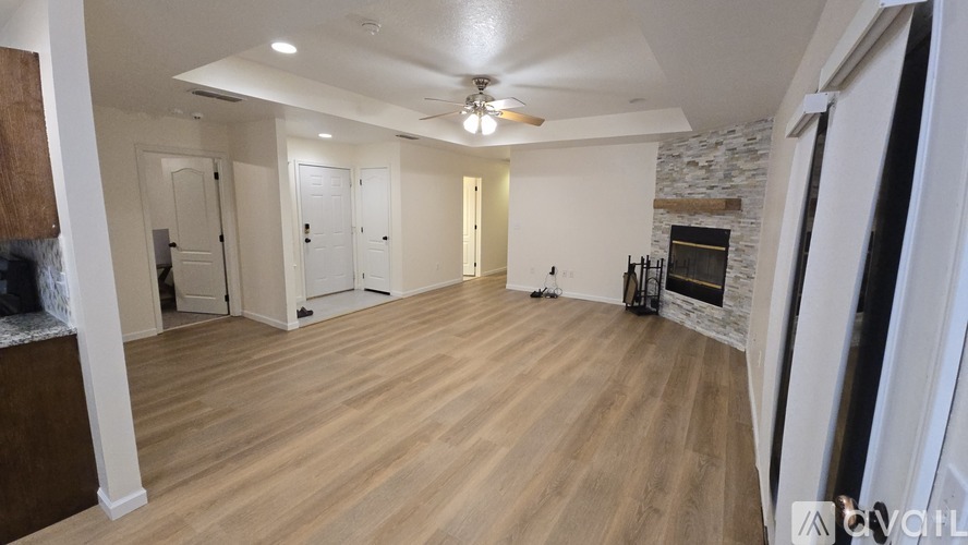 A spacious room with wooden flooring and a stone fireplace.