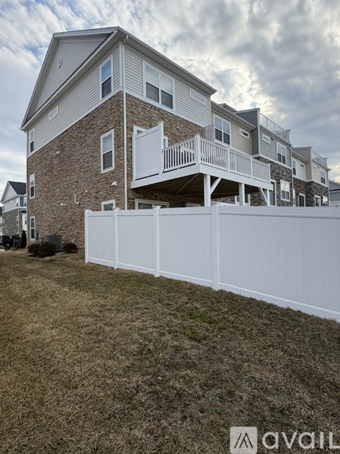 A white fence in front of a two-story building.