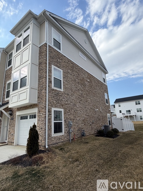 A two-story brick house with a garage on the first floor and a balcony on the second floor.