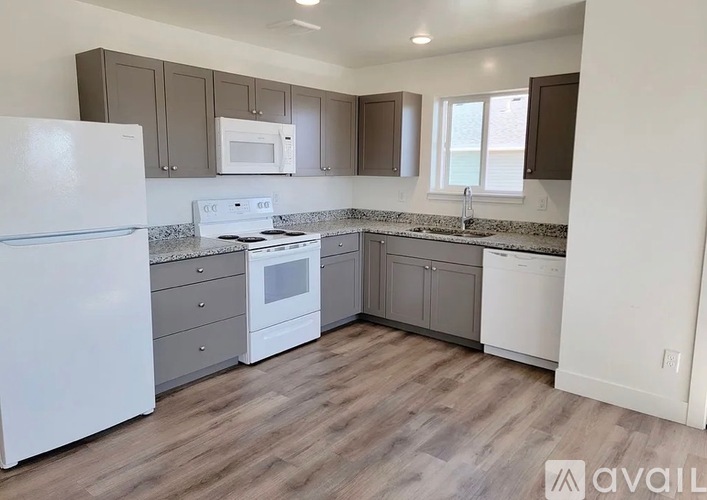 A kitchen with white appliances and wooden floors.