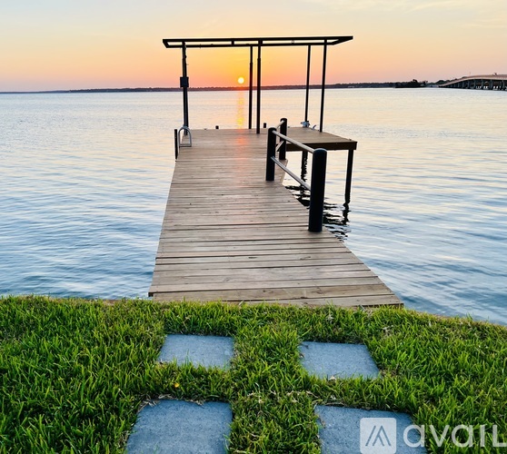 A wooden dock extends into a calm body of water at sunset.