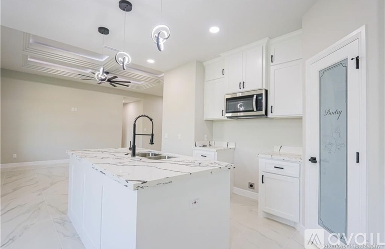 A kitchen with white cabinets and a marble countertop.