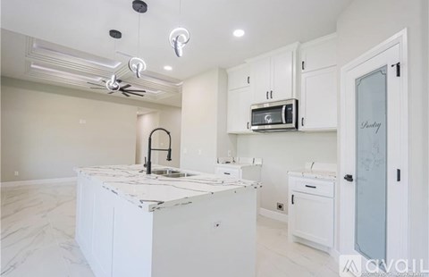 A kitchen with white cabinets and a marble countertop.