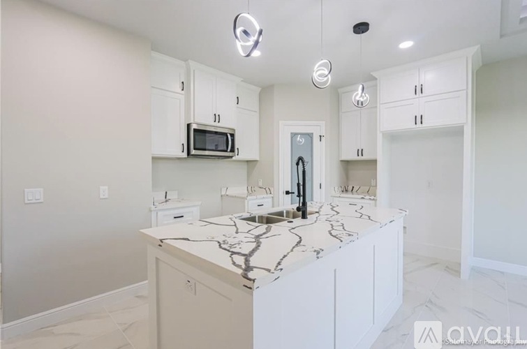 A kitchen with white cabinets and a marble countertop.