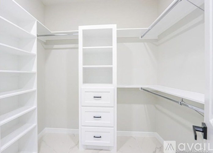 A white walk-in closet with drawers and shelves.