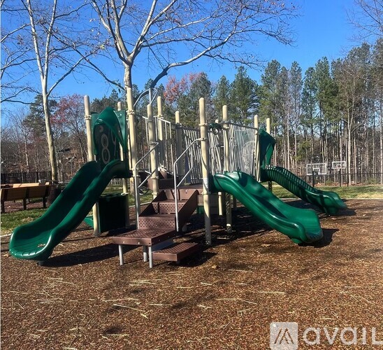 A playground with a green slide and a wooden structure.