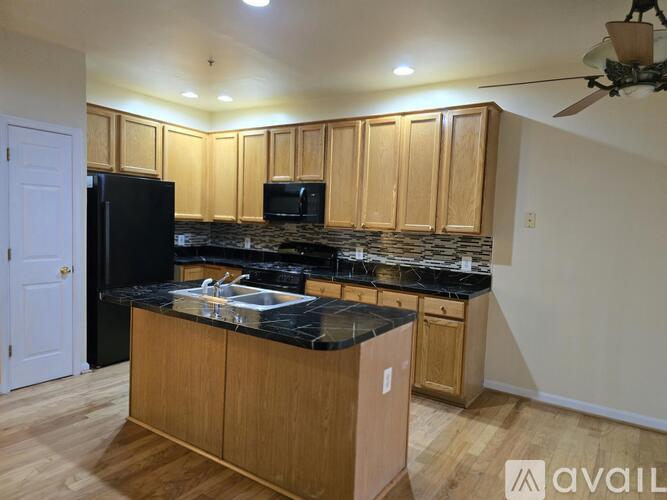 A kitchen with wooden cabinets and black countertops.