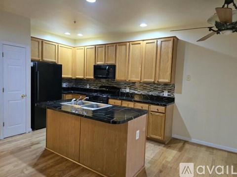 A kitchen with wooden cabinets and black countertops.