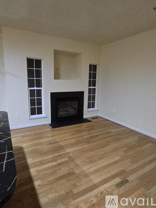 A living room with a fireplace and wooden floors.
