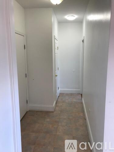 A hallway with tiled floors and white walls.