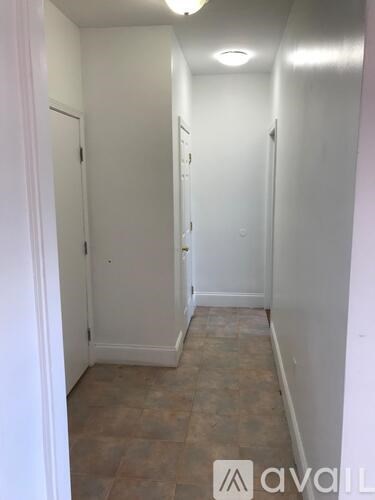 A hallway with tiled floors and white walls.
