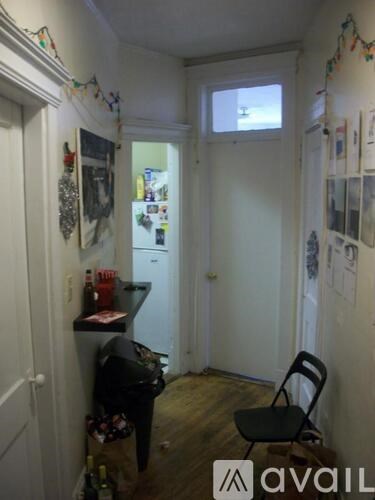A small kitchen with a fridge, a chair and a table.
