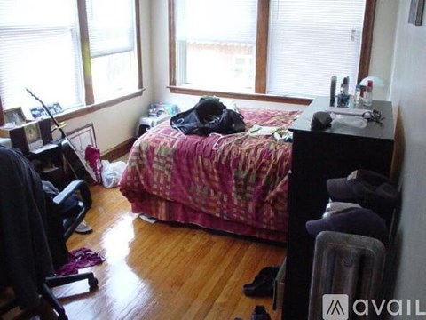 A bedroom with a bed, desk, chair, and window.