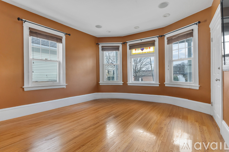 A room with wooden flooring and three windows.