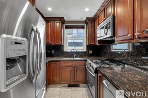 A modern kitchen with wooden cabinets and a stainless steel refrigerator.