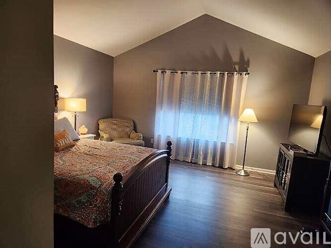 A bedroom with a large bed and a chair.
