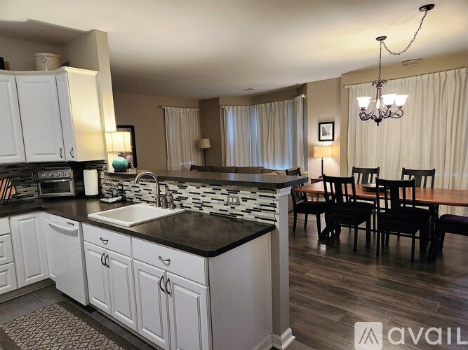 A kitchen with white cabinets and a black countertop.