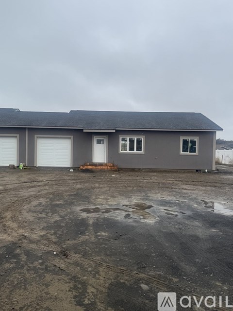 A grey house with a black roof and a white garage door.