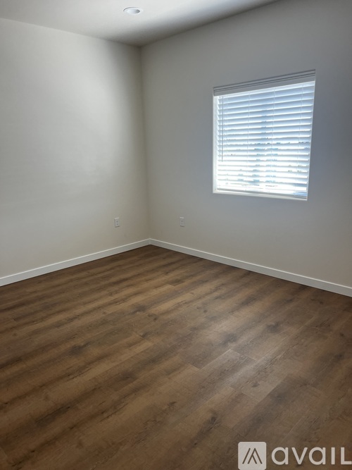 A room with wooden flooring and a window with blinds.