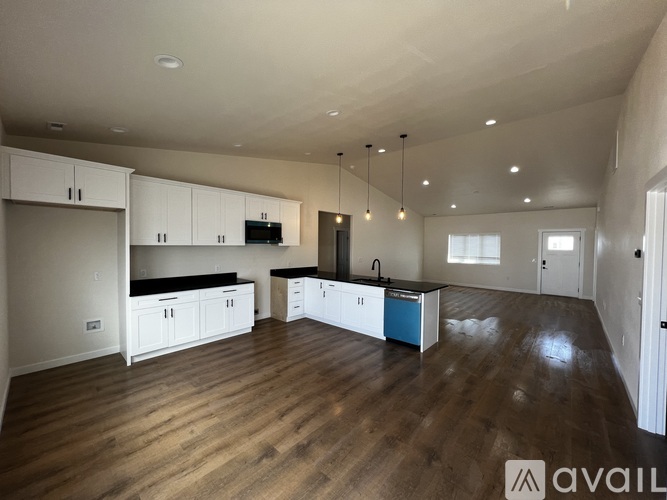 A spacious kitchen with wooden floors and white cabinets.