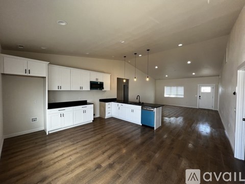 A spacious kitchen with wooden floors and white cabinets.