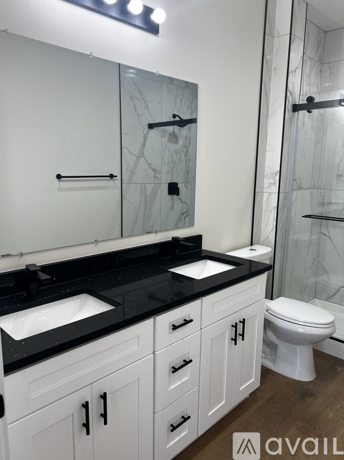 A bathroom with a black counter top and white cabinets.