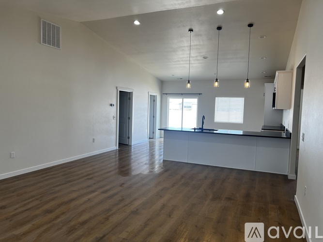 A spacious room with wooden floors and a bar area.