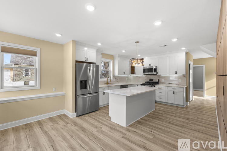 A modern kitchen with wooden floors and stainless steel appliances.