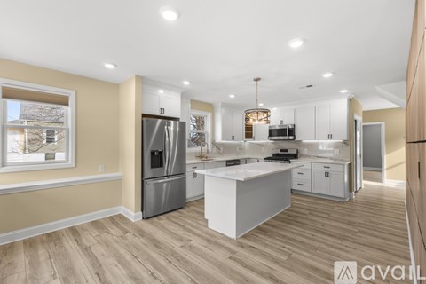 A modern kitchen with wooden floors and stainless steel appliances.