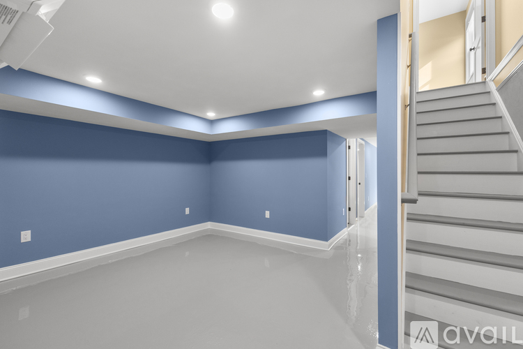 A spacious room with a staircase on the right side.