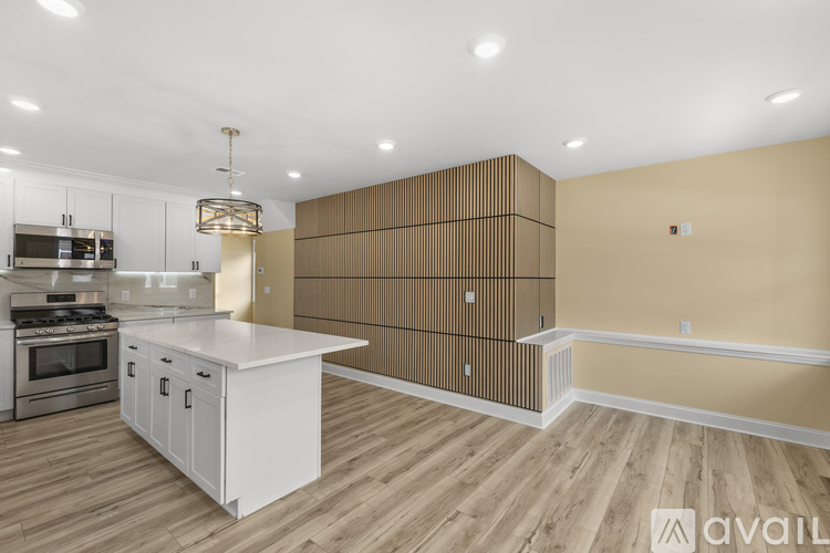 A modern kitchen with wooden floors and white cabinets.