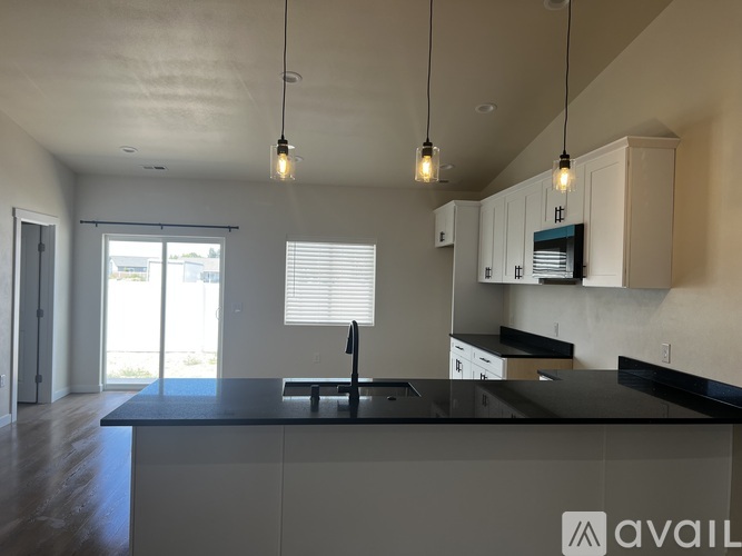 A modern kitchen with a black countertop and white cabinets.