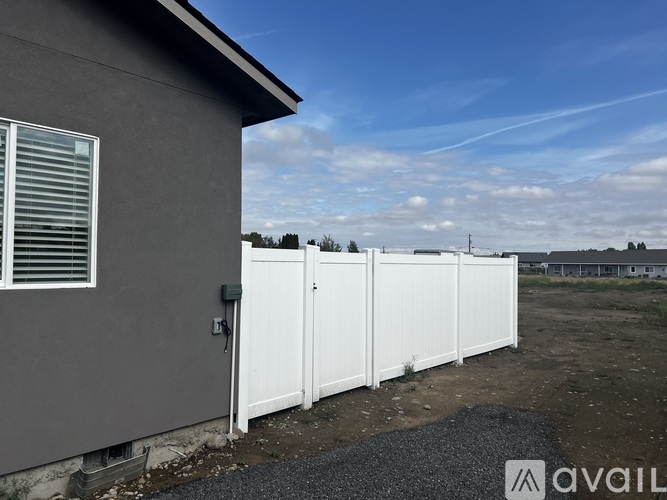 A grey house with a white fence in front of it.