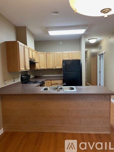 A kitchen with wooden cabinets and a black refrigerator.