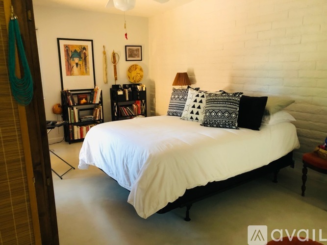 A bedroom with a white bed and a white brick wall.