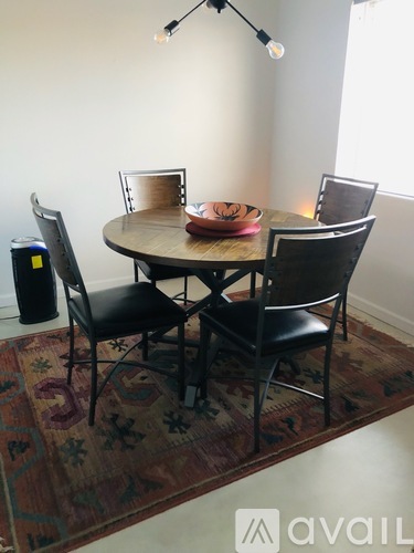 A table with four chairs and a rug in front of it.