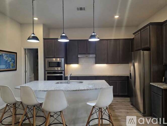 A kitchen with a marble countertop and white chairs.