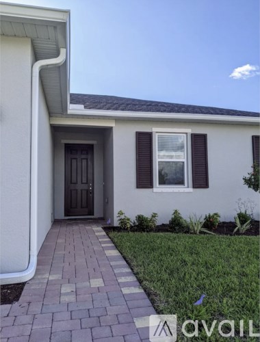 A house with a brown door and a brick pathway leading to it.