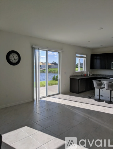 A kitchen with a bar stool and a clock on the wall.