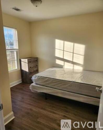 A bedroom with a bed, dresser, and window.